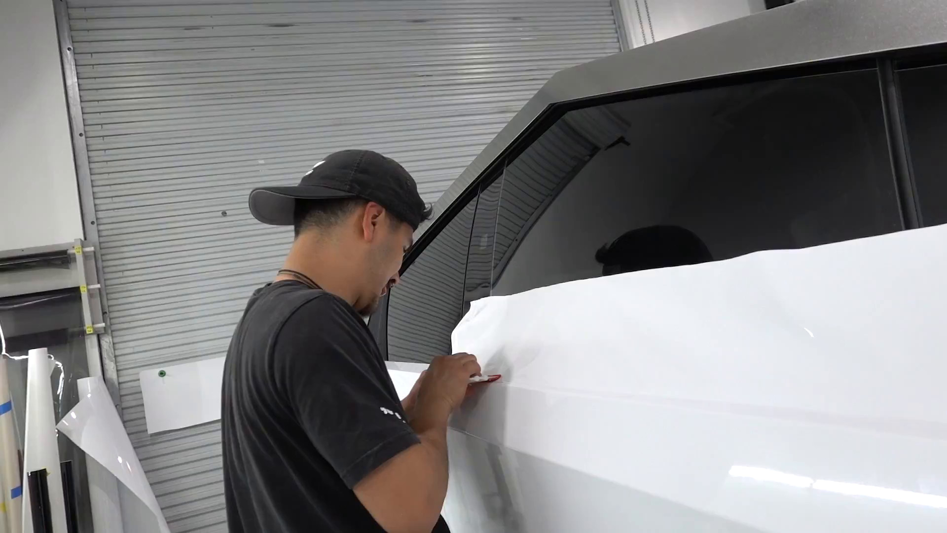 Installer wrapping a Cybertruck door in gloss white vinyl